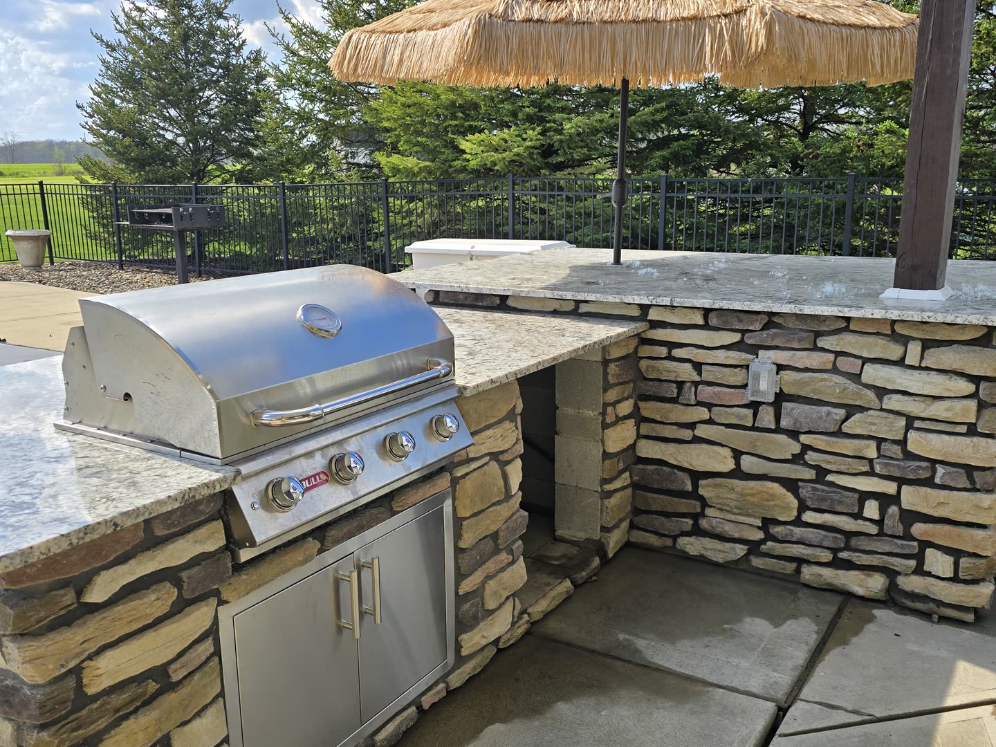 Built-in stainless steel grill within a custom stone outdoor kitchen