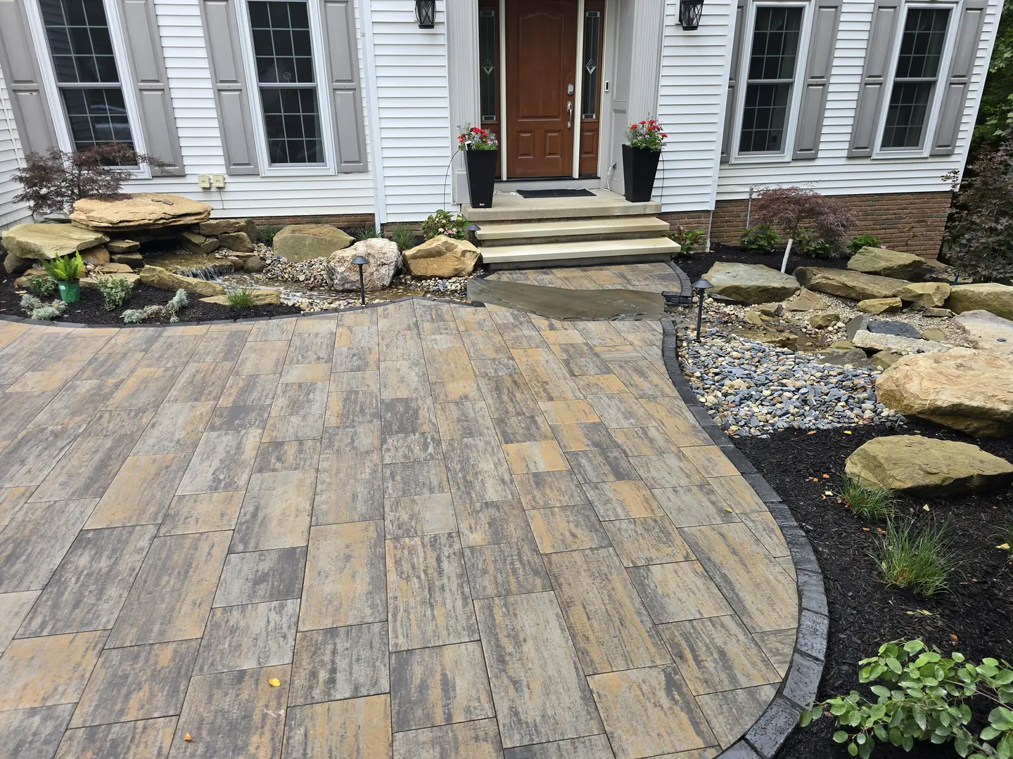 Finished paver driveway and landscaped front entry at a Stow property