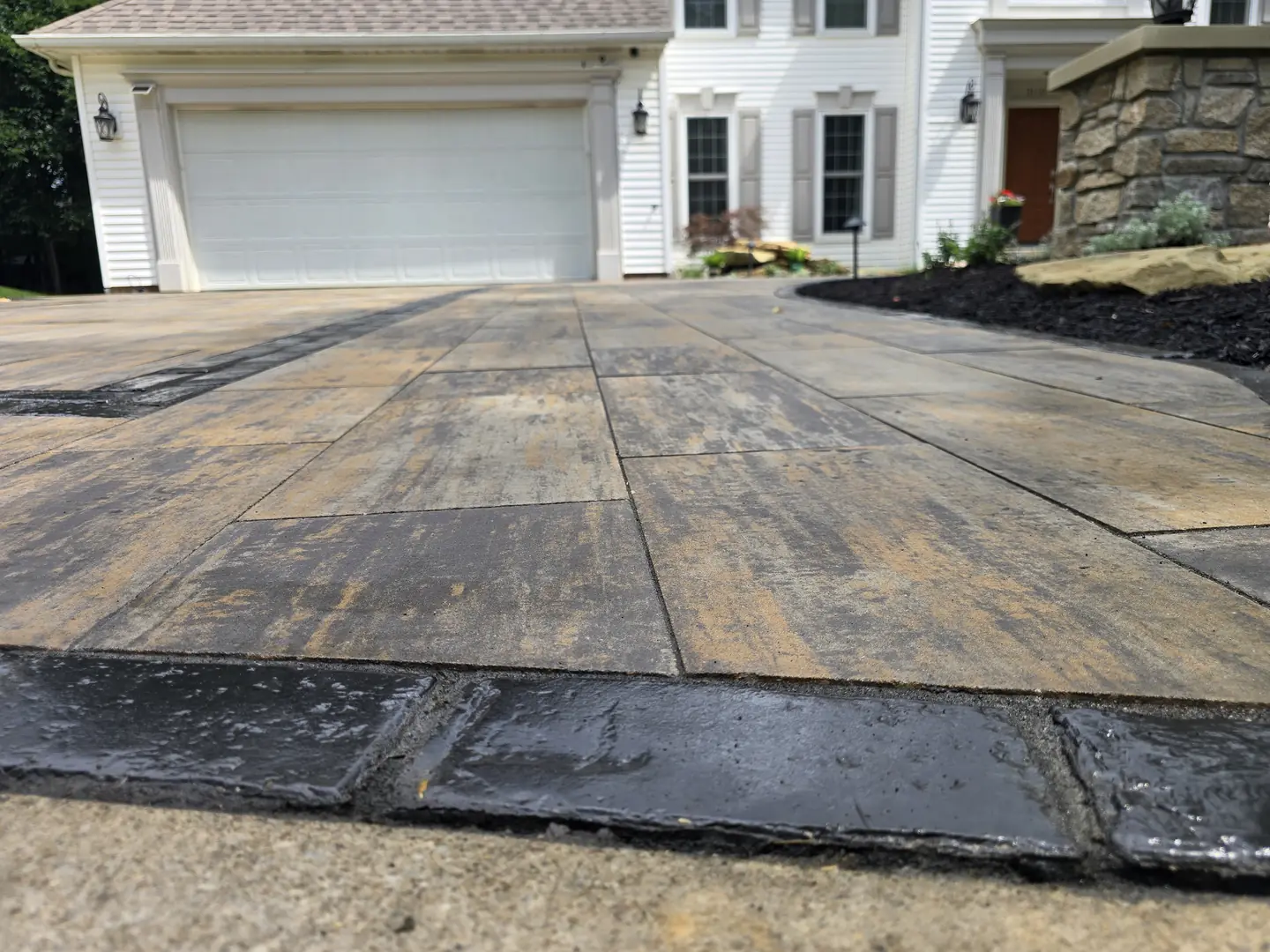 Finished paver driveway and landscaped front entry at a Stow property