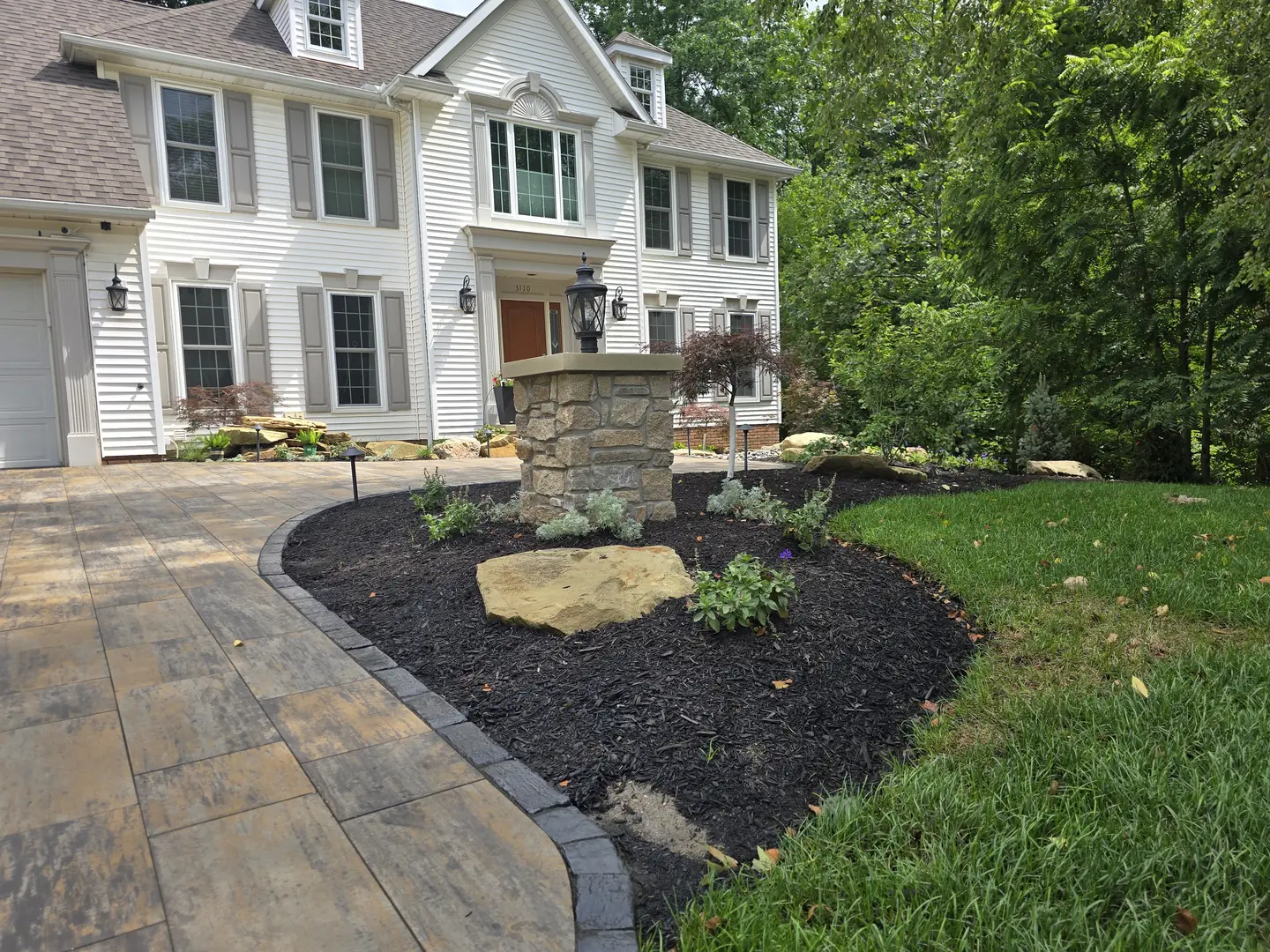 Completed Stow front landscape with natural stone, shrubs, and lighting