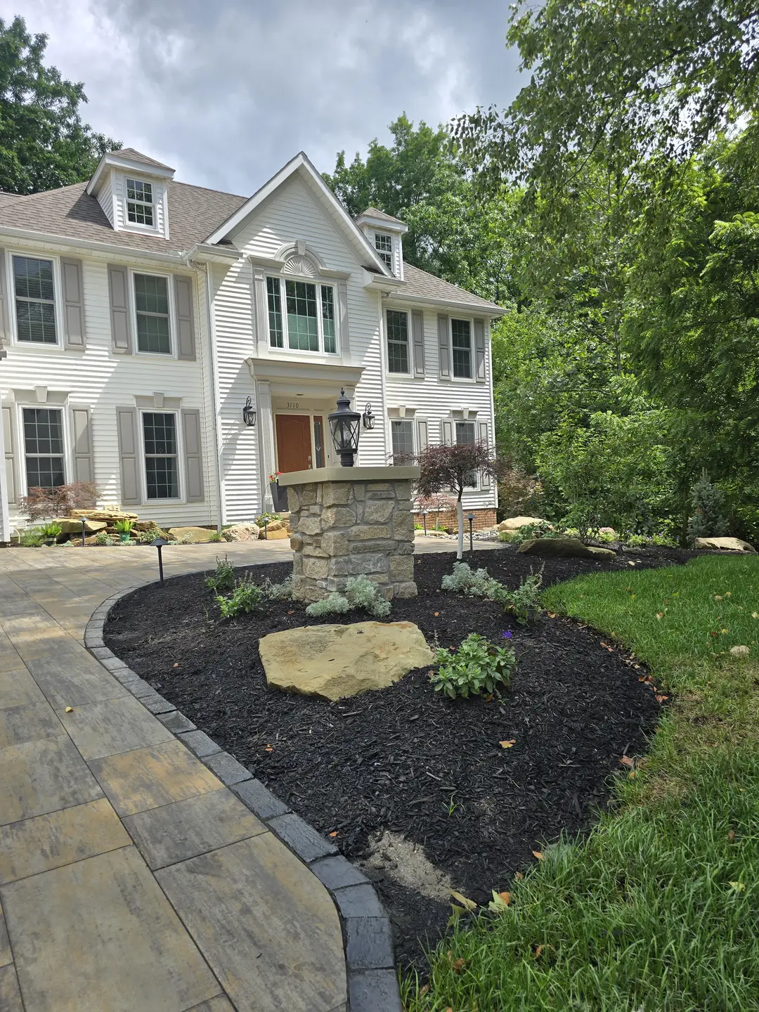 Completed Stow front landscape with natural stone, shrubs, and lighting