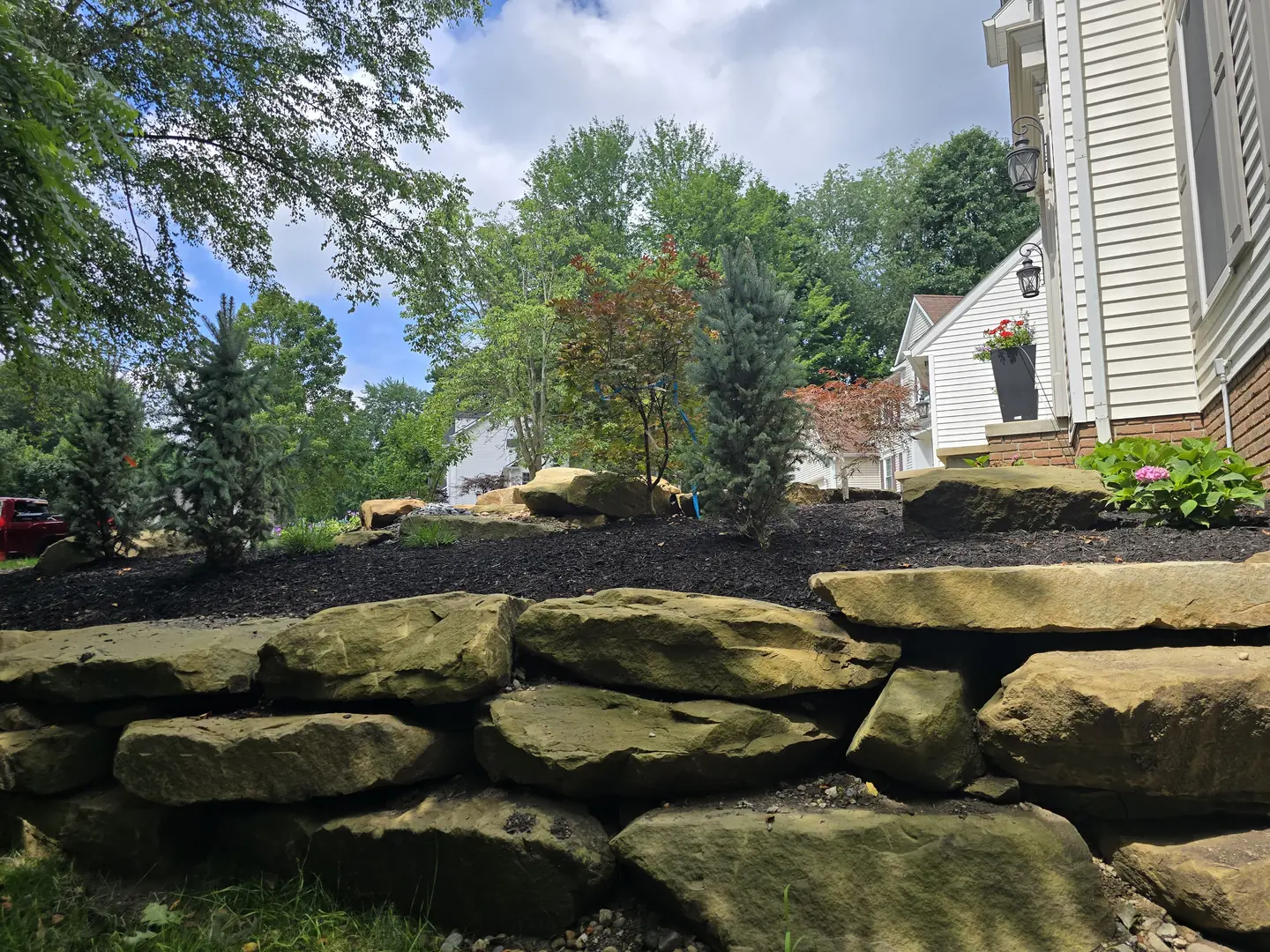 Completed Stow front landscape with natural stone, shrubs, and lighting
