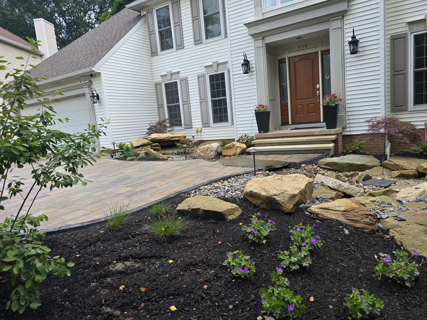 Completed Stow front landscape with natural stone, shrubs, and lighting