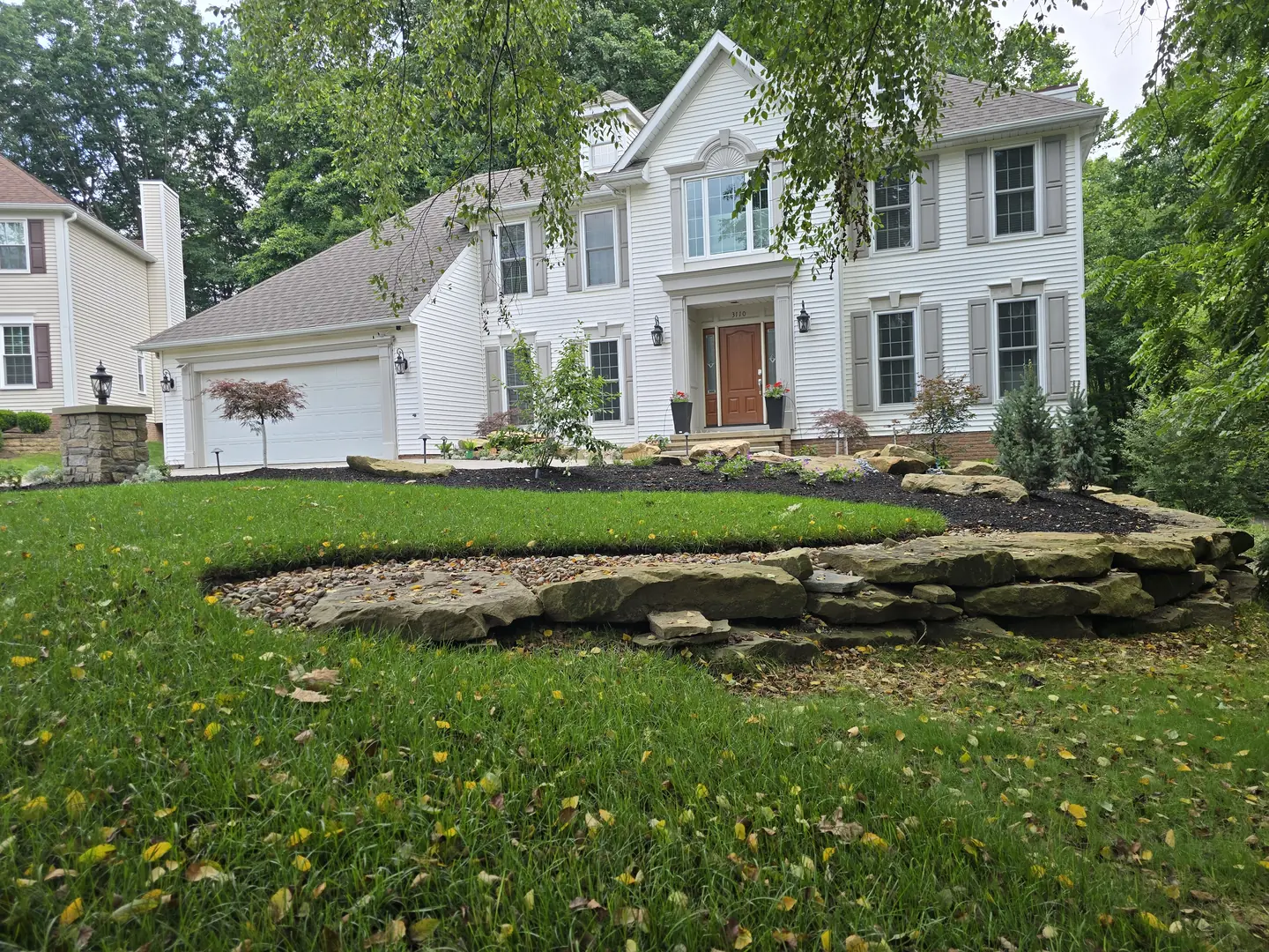 Completed Stow front landscape with natural stone, shrubs, and lighting