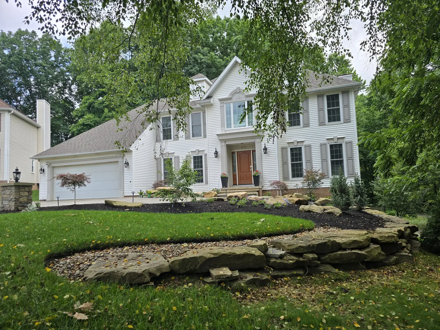 Completed Stow front landscape with natural stone, shrubs, and lighting