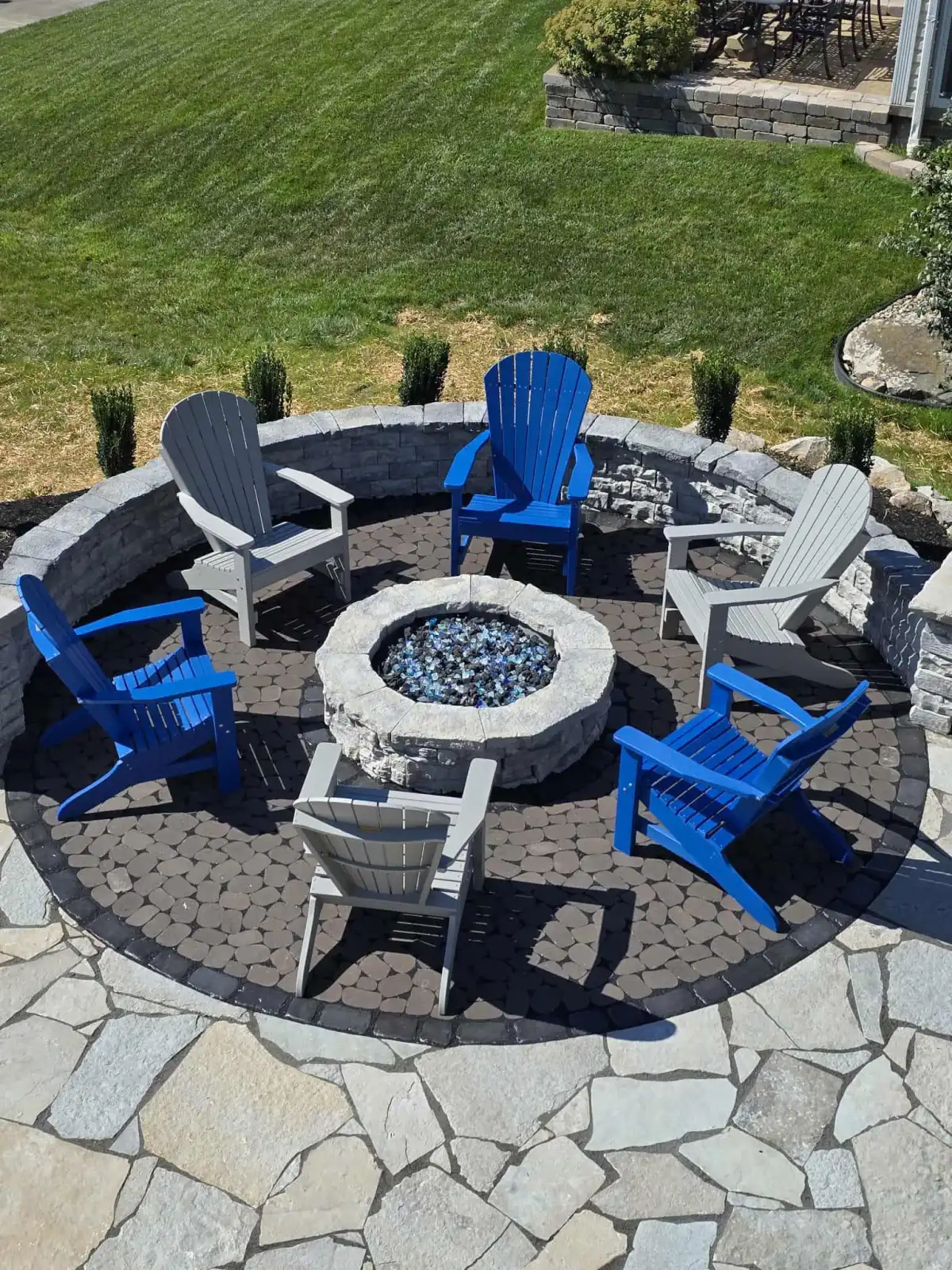 Custom outdoor fire pit with stone seating wall in a Northeast Ohio backyard