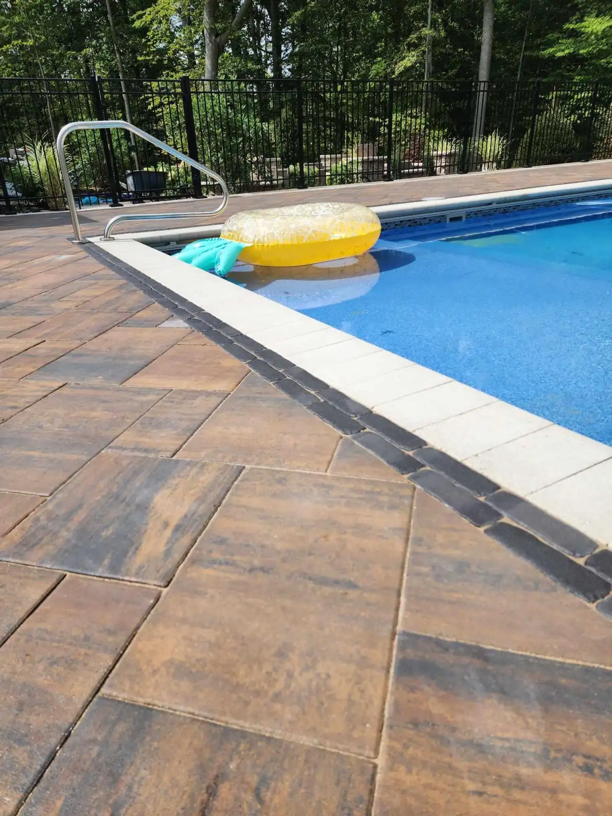Paver pool deck with large-format dark bronze pavers