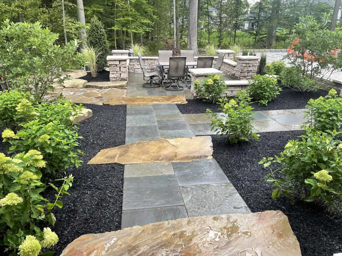 Flagstone path through landscaped beds to stone-pillar dining patio with hydrangeas