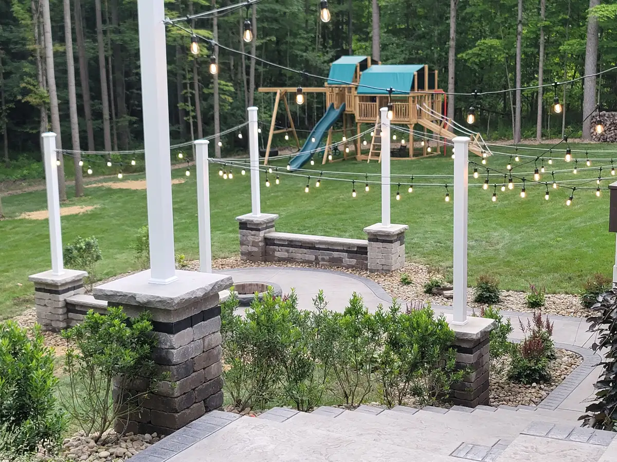 Backyard patio with stone pillars, sitting walls, and string lights