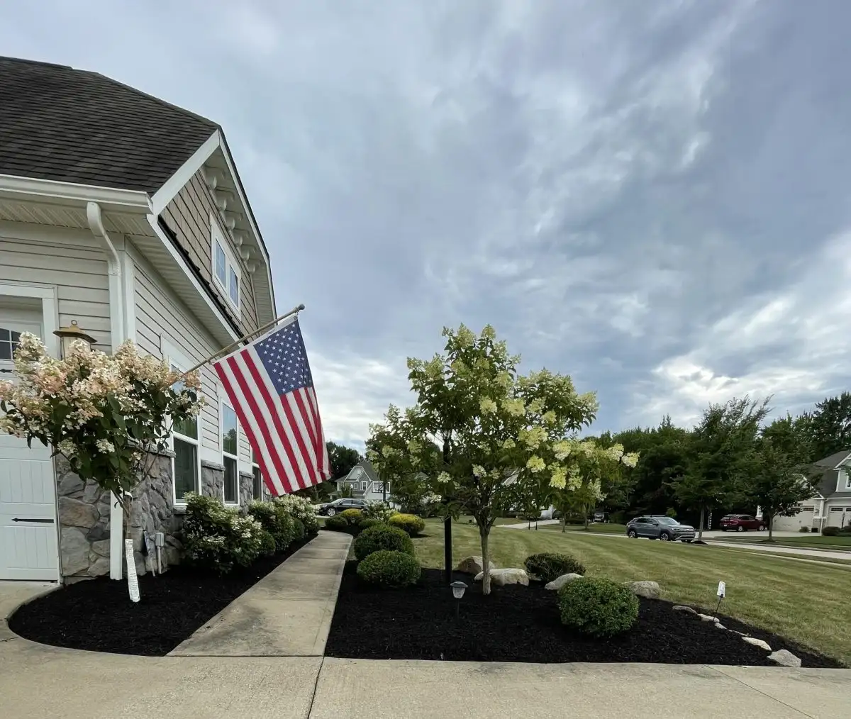 House with American flag, hydrangeas, and fresh mulch