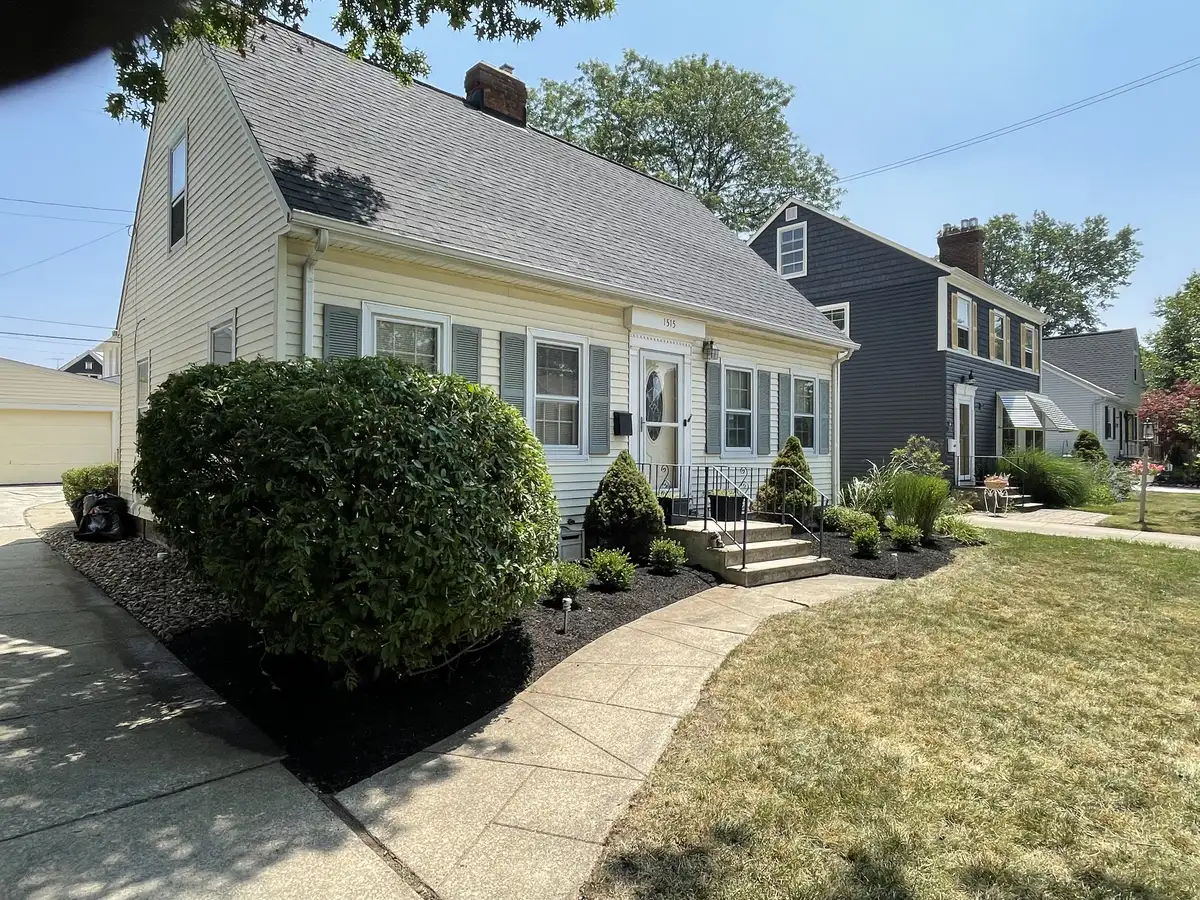 Front-yard landscape with a curved walkway, layered shrubs, ornamental grasses, and fresh dark mulch