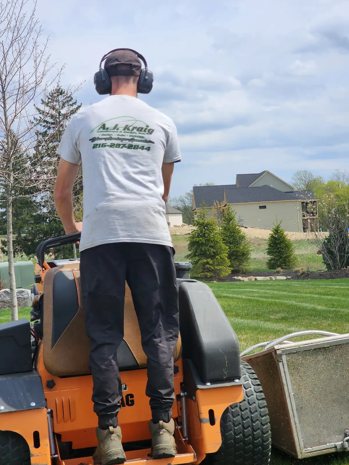 A.J. Kraig crew member operating a commercial mower on a striped lawn