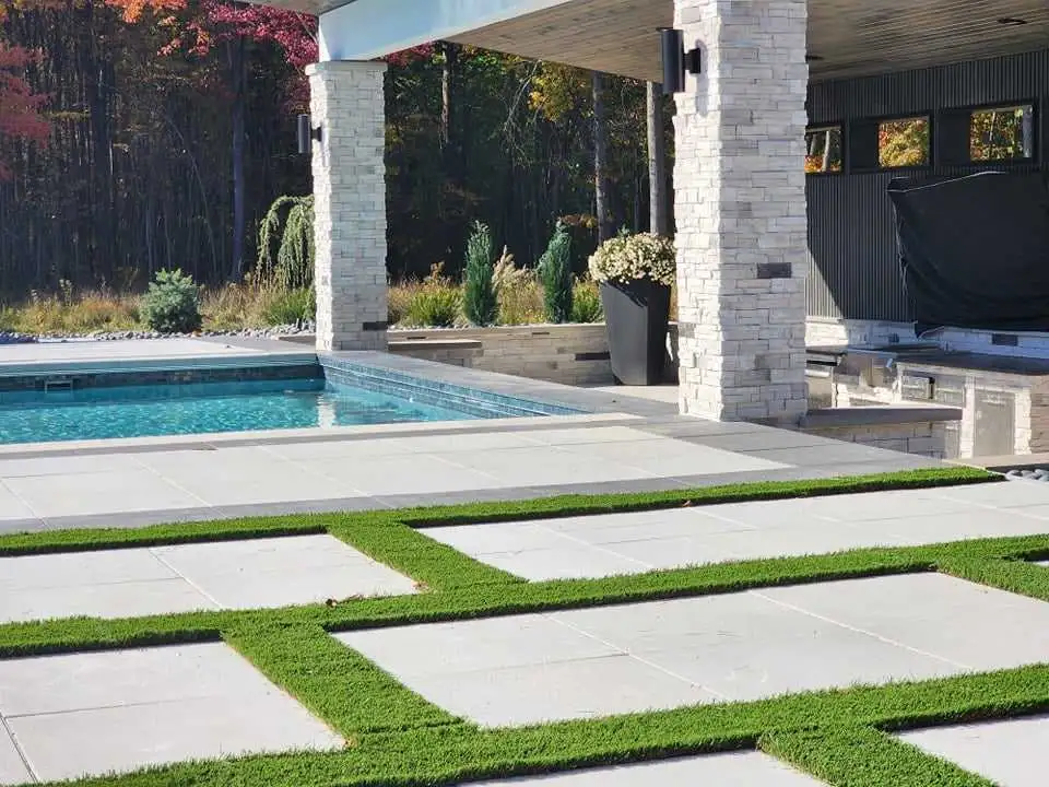 Pool area with synthetic turf and stone pillars