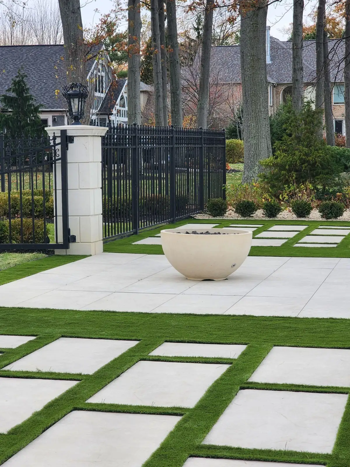 Synthetic turf with paver grid and fire bowl in luxury backyard
