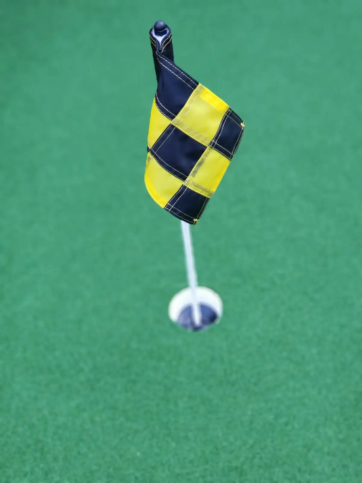 Putting green flag and cup close-up on synthetic turf